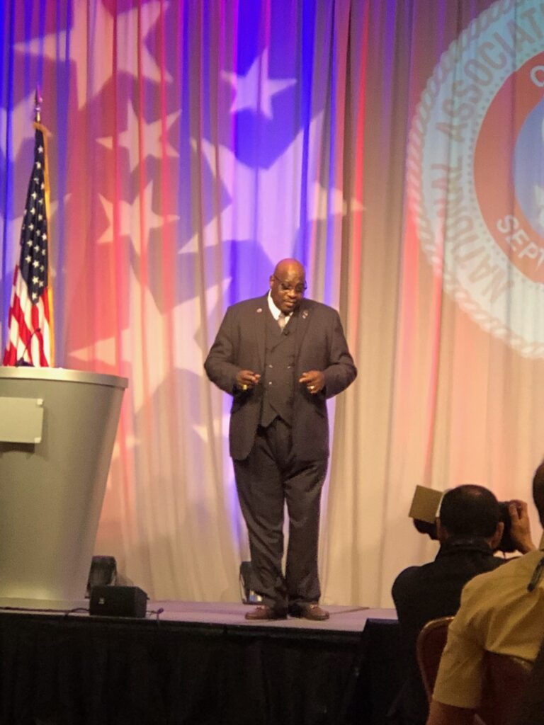 A speaker in formal attire stands on stage