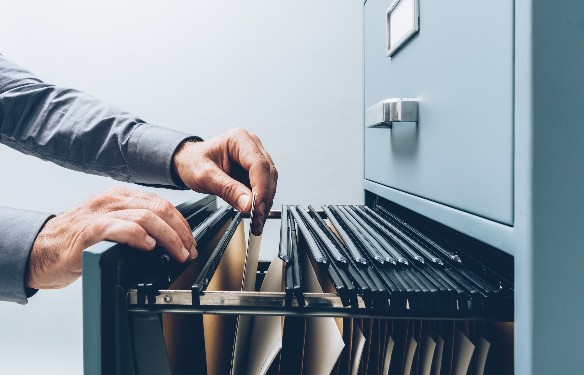 Office clerk searching for files into a filing cabinet drawer